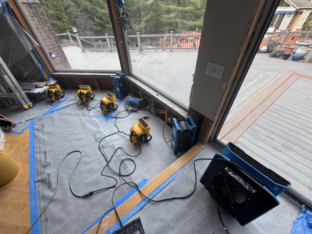 Air movers and drying equipment set up around a water-damaged doorway during a restoration job