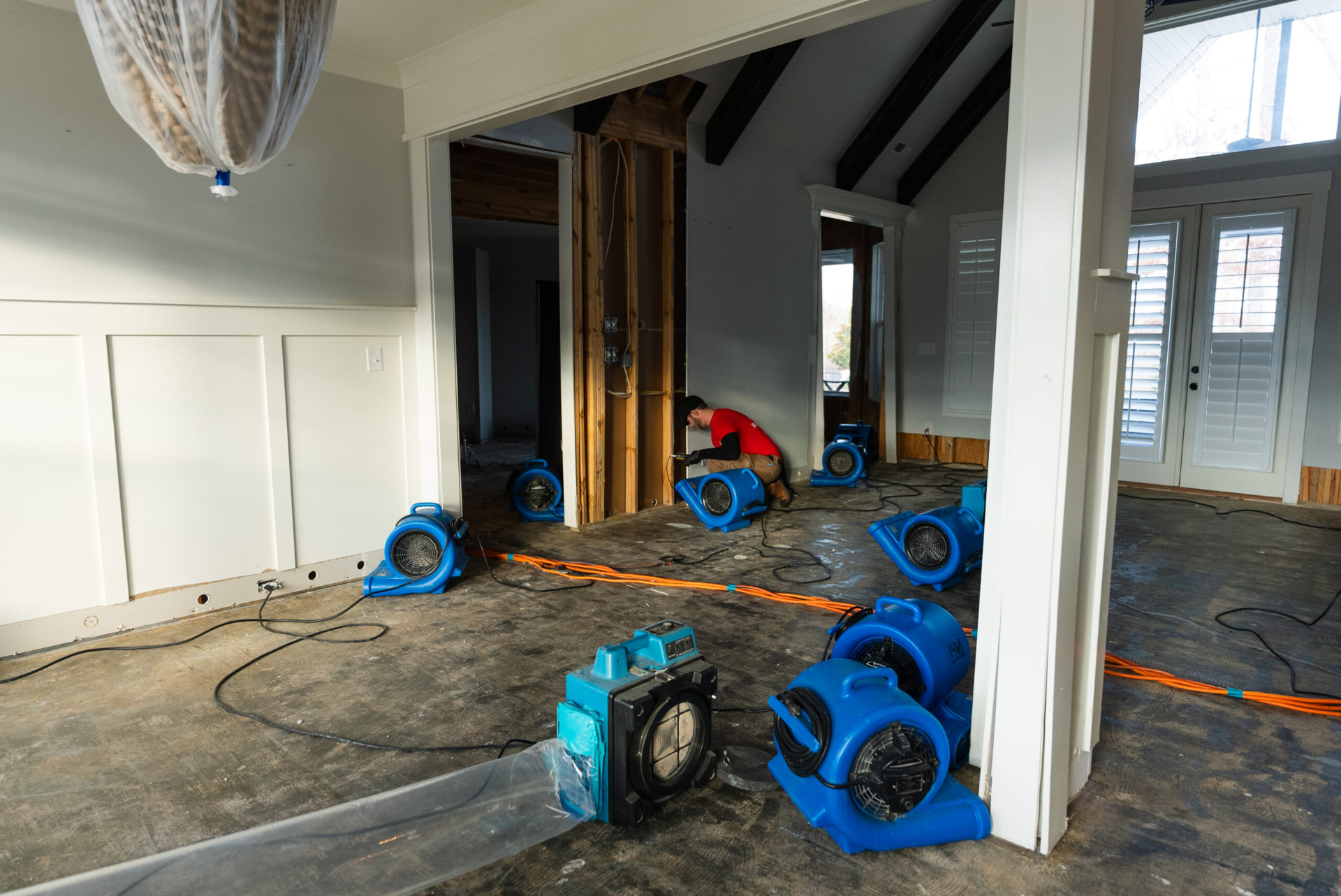 Technician working amid air movers and an air scrubber drying out a flood-damaged home interior